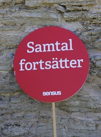 Röd skylt med texten "Samtal fortsätter"