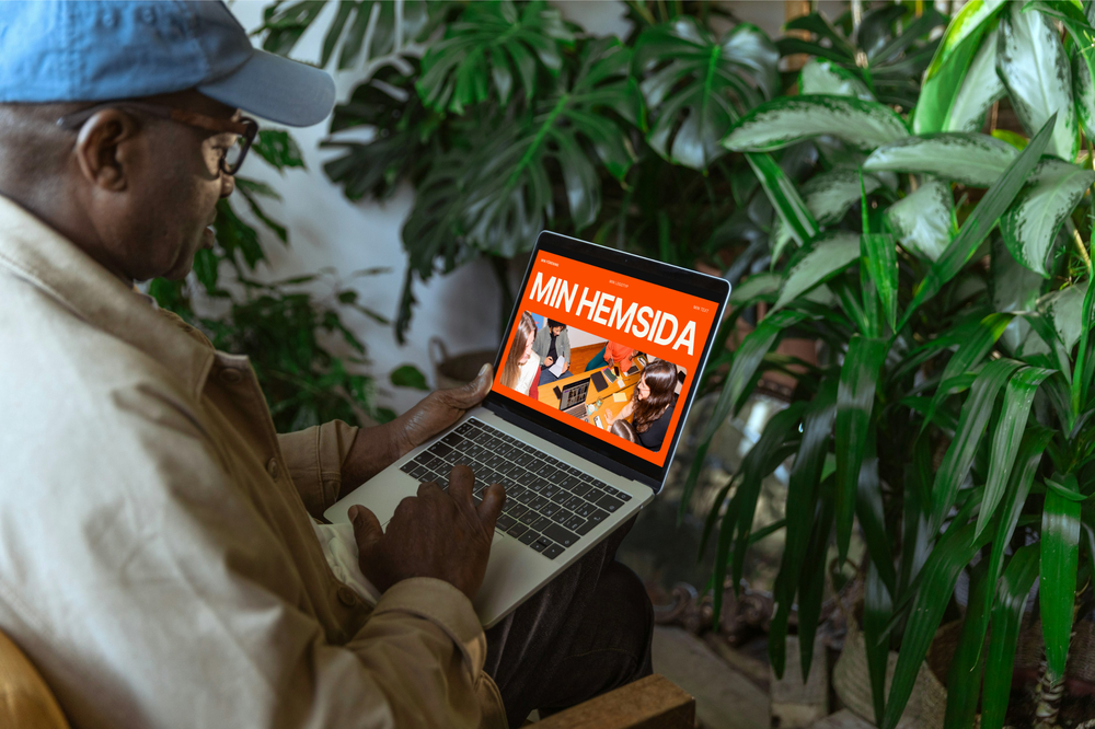 En man sitter med en laptop där man ser hans nya hemsida.
