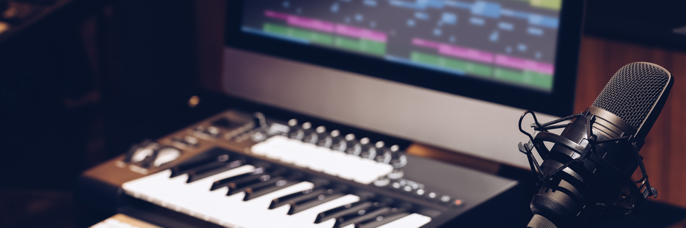 Ett midi keyboard, en mikrofon och en datorskärm med inspelningsprogram.