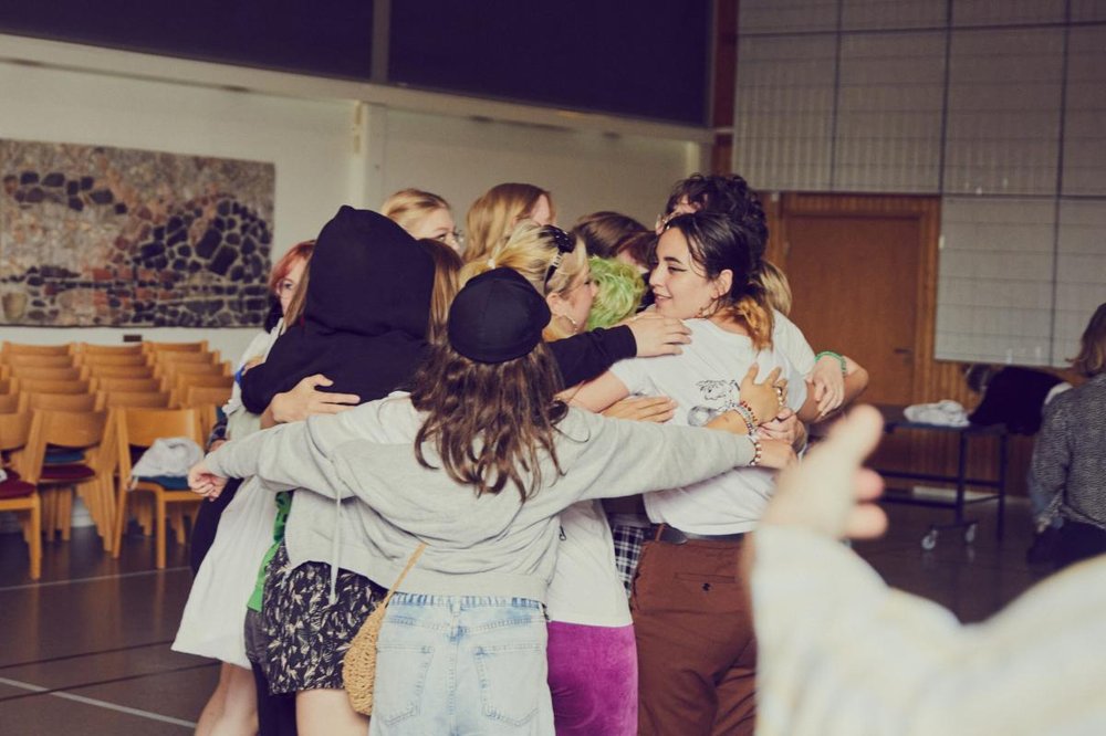Bild på människor i grupp som kramas och håller om varandra.