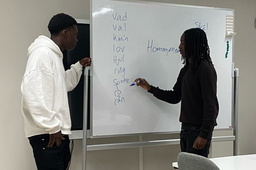 Två unga killar skriver på en whiteboard