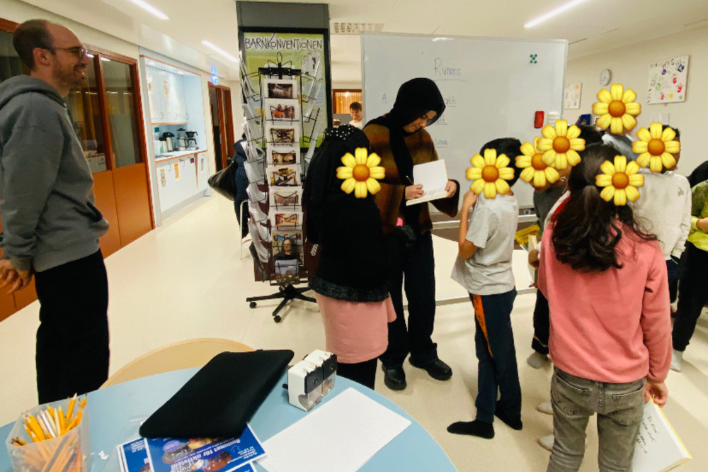 En kvinna skriver autografer till några unga deltagare.